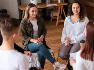 Eine Gruppe von jungen Menschen dsitzen im Kreis besammen und unterhalten sich. Die Atmosphäre ist sehr positiv.