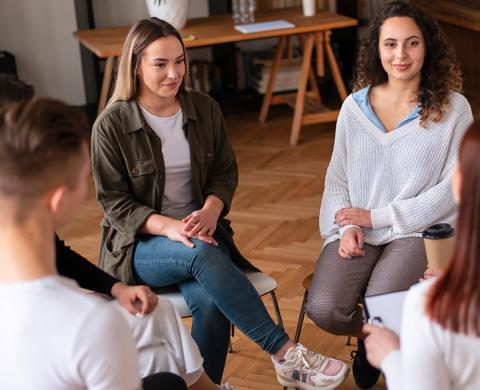 Eine Gruppe von jungen Menschen dsitzen im Kreis besammen und unterhalten sich. Die Atmosphäre ist sehr positiv.